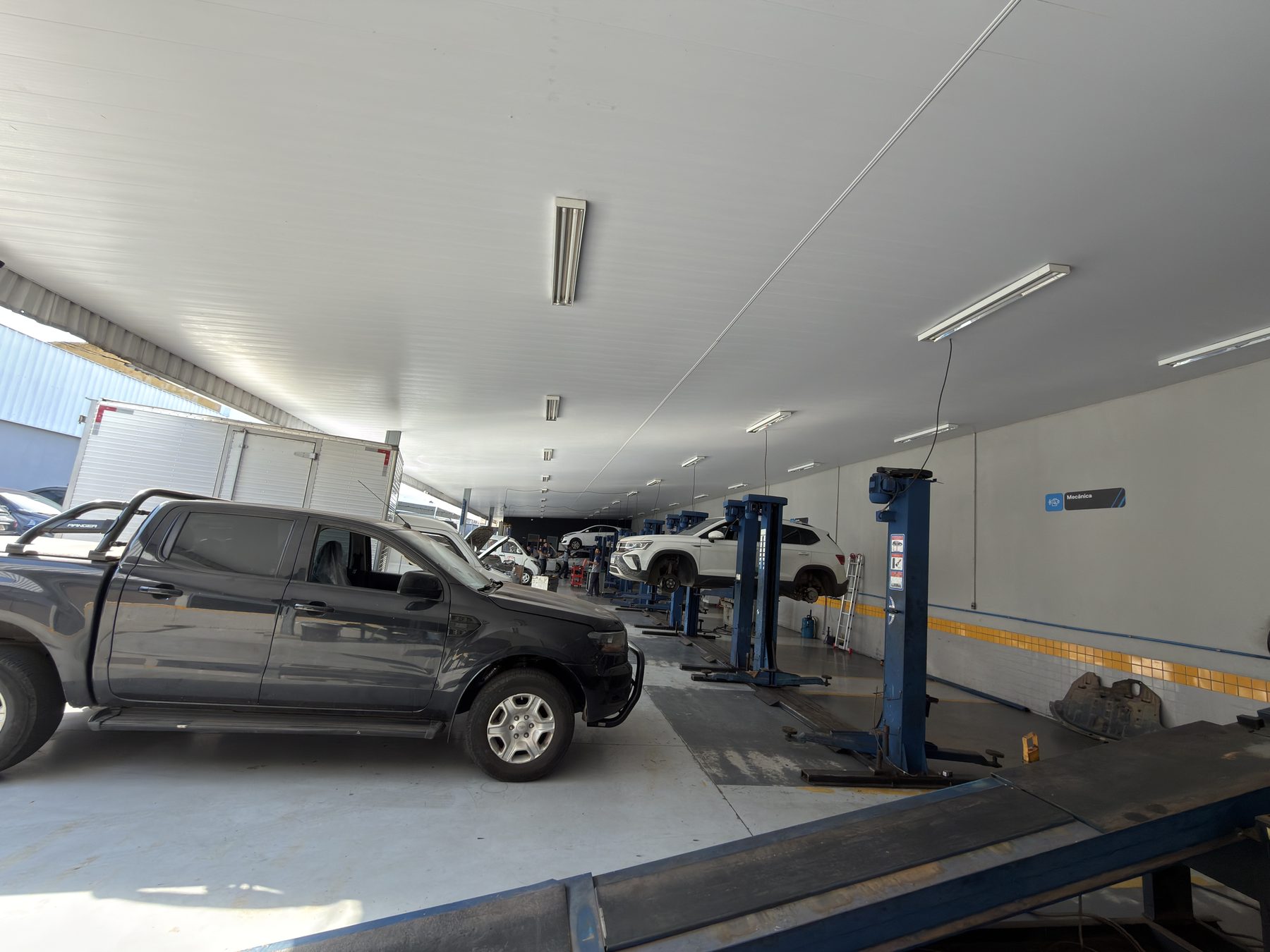 Galpão de serviço do Centro Automotivo Âncora, com carros suspensos nos elevadores